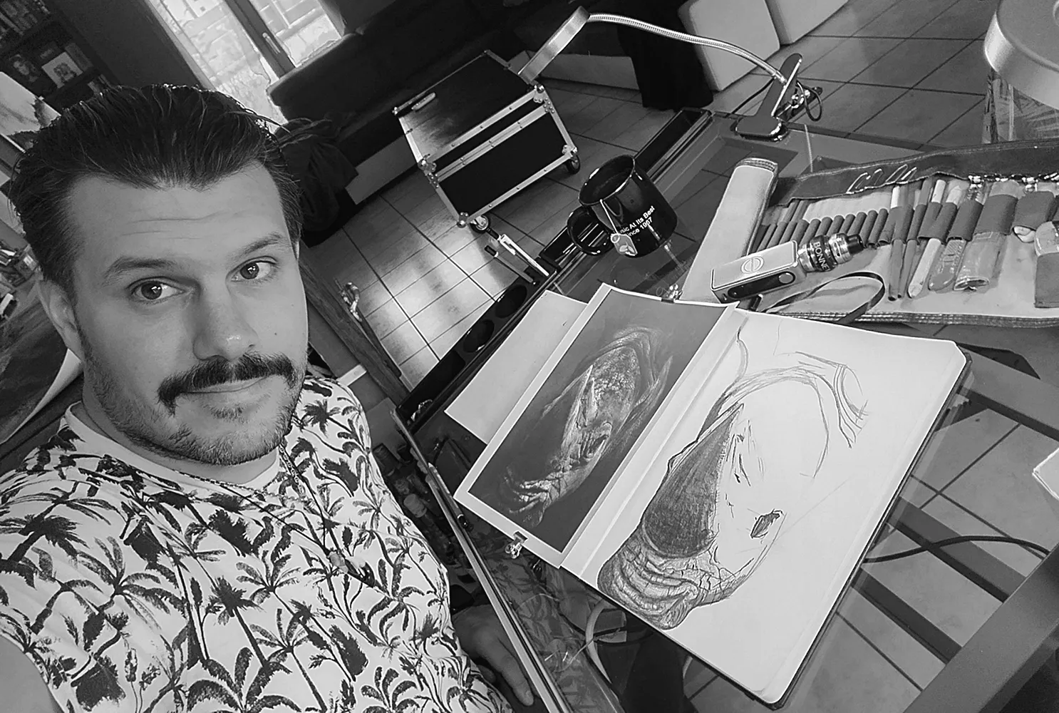 Jérémy Morin réalisant un dessin de rhinocéros au graphite, autoportrait en noir et blanc dans son atelier