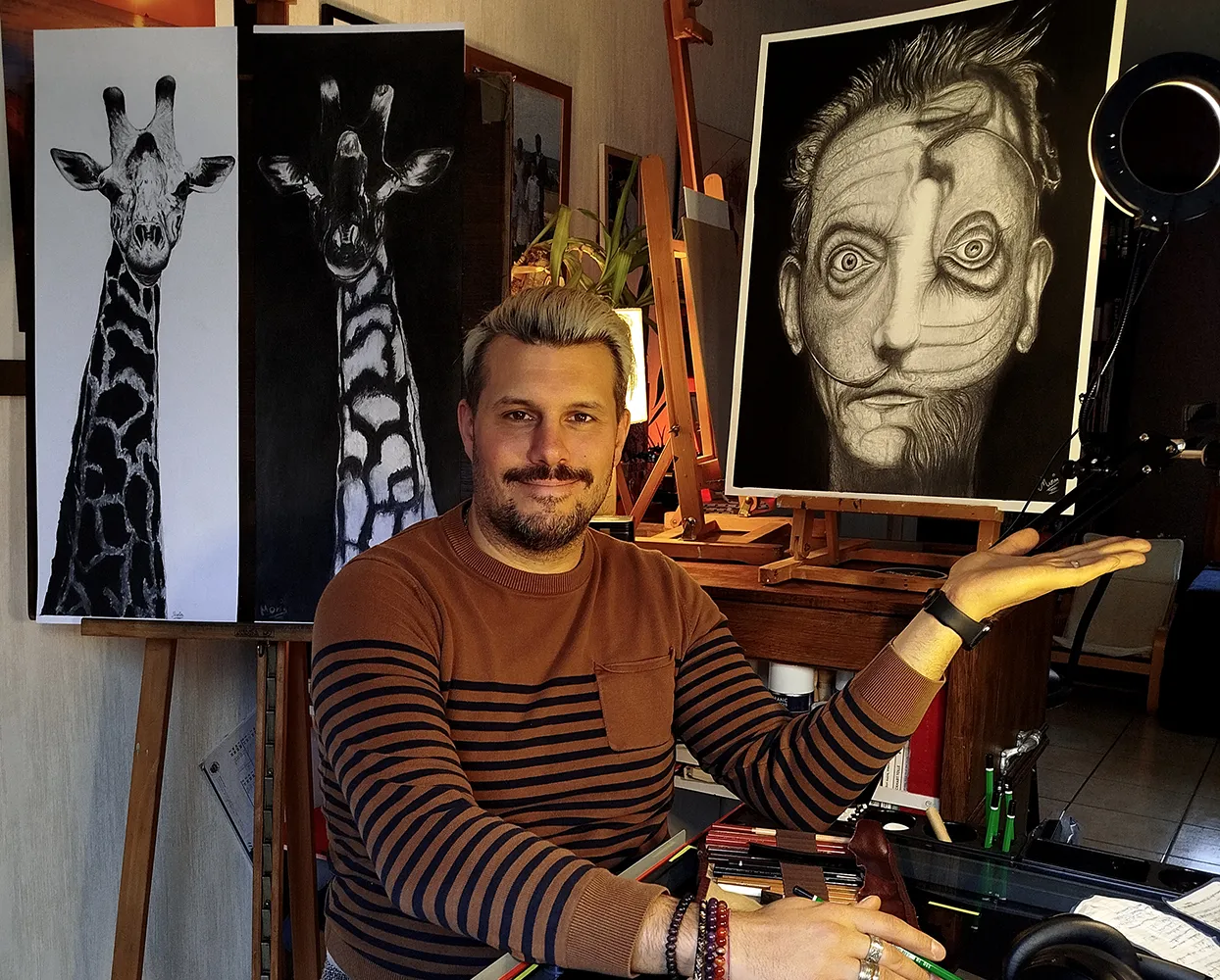 Jérémy Morin dans son atelier devant ses œuvres terminées, dont deux girafes et la série Fractali