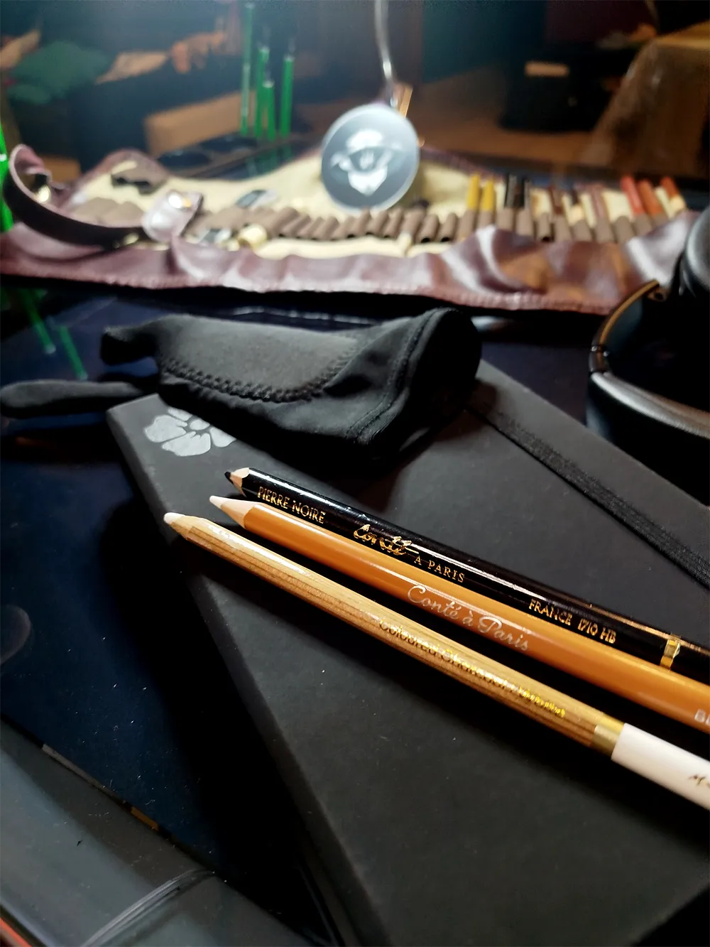Outils de dessin utilisés pour un portrait hyperréaliste en noir et blanc : pierre noire, craie blanche Conté et gant de dessin