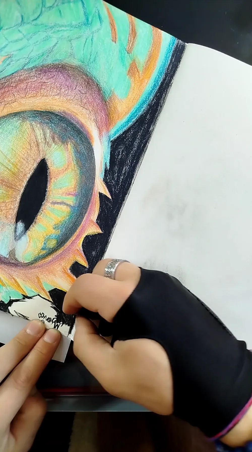 Main de Jérémy Morin dessinant les détails d’une œuvre colorée